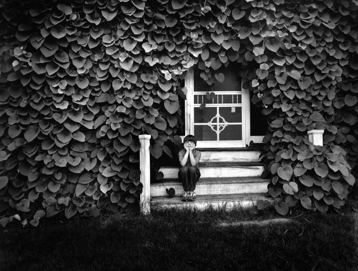 Boy on a porch covered with Dutchman's Pipe vine